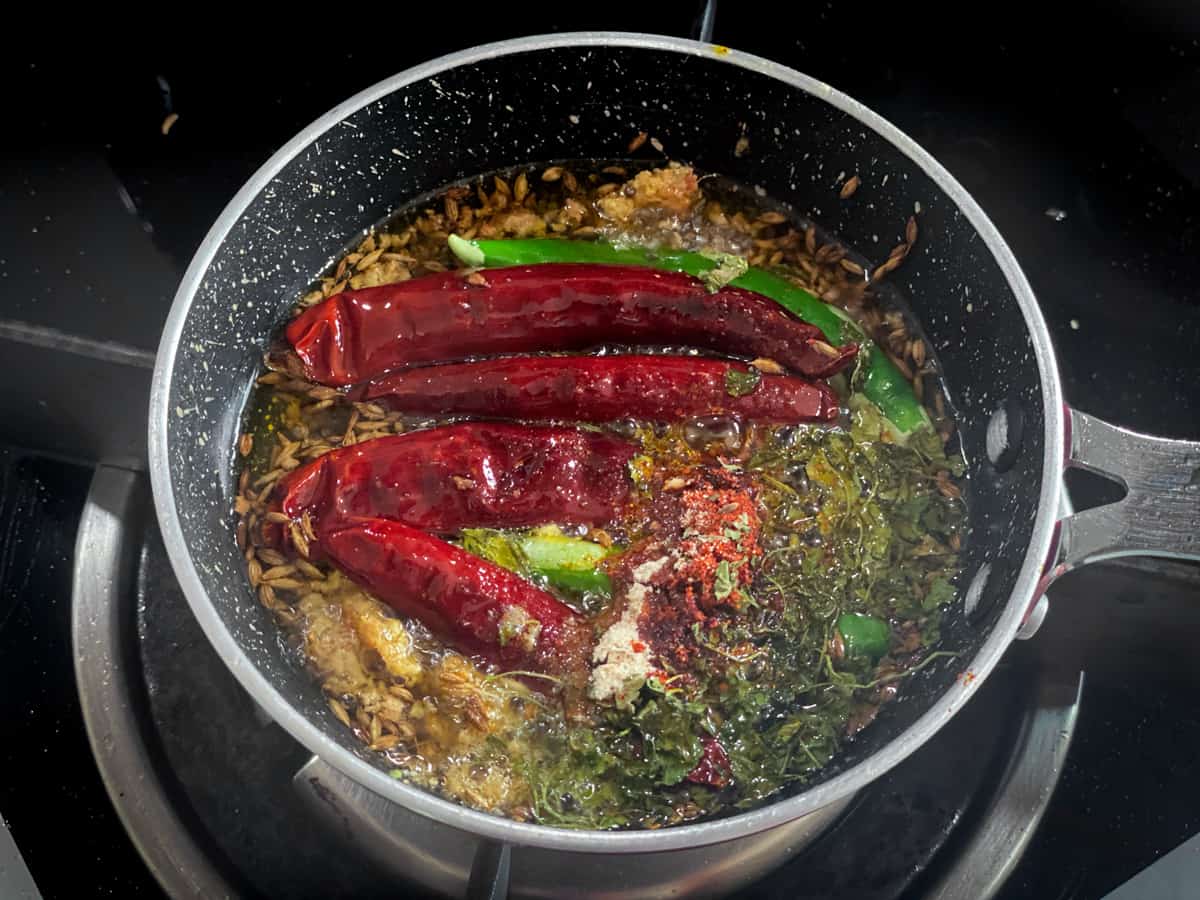 Green and red chilies, dried fenugreek, asafoetida added to the small with ghee, mustard, cumin and ginger.