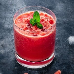 short rocks glass of watermelon juice on ice with a sprig of mint