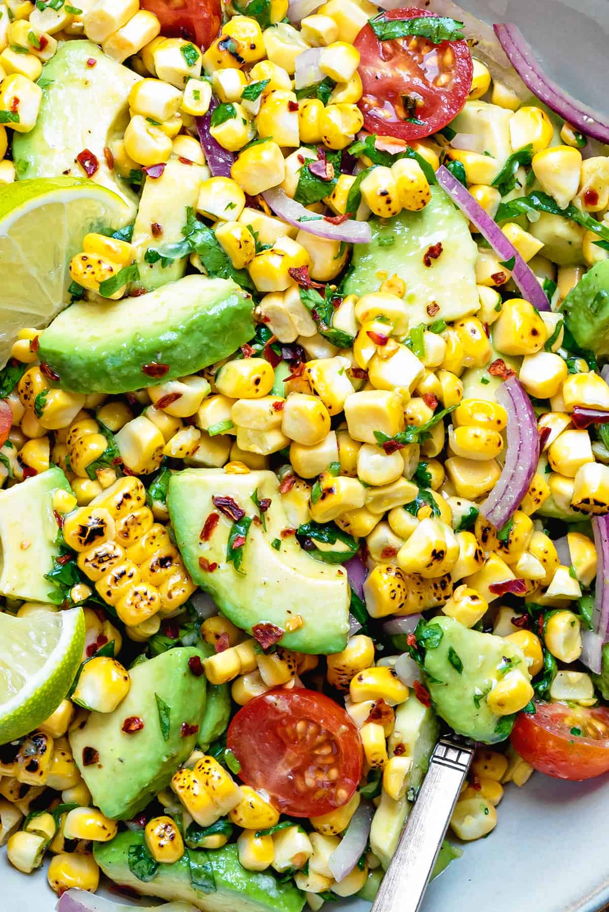 a close up shot of tomato avocado corn salad in bowl 