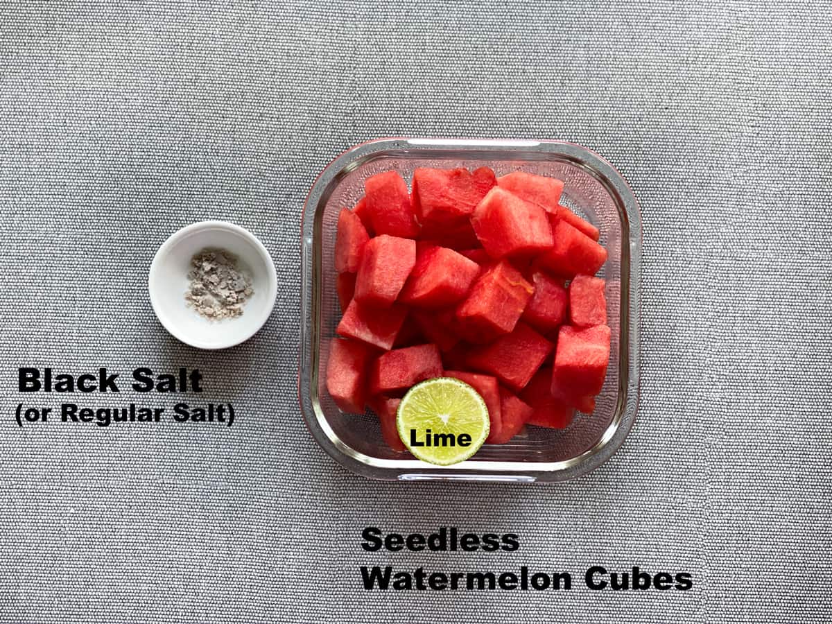 overhead shot of cubed watermelon, half a lime, black salt and pepper laid out to make fresh watermelon juice