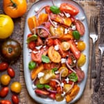 close up shot of heirloom tomato salad with feta cheese on a grey oval platter