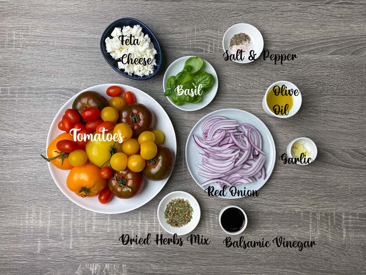 ingredients for garden fresh tomato salad laid out on a wooden table