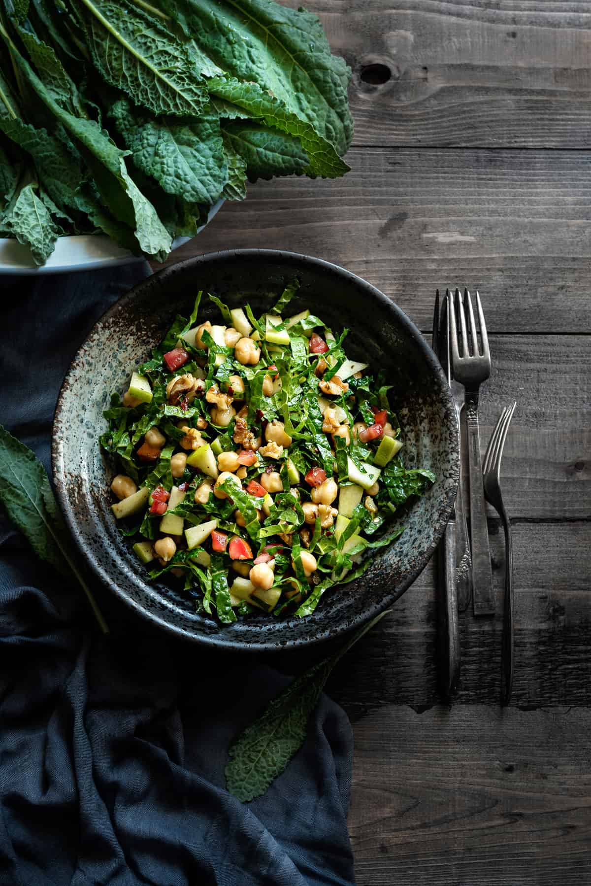 overhead shot of a bowl of tuscan kale and apple salad with walnuts, chickpeas and tomatoes