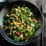 kale apple salad in a grey speckled bowl on a grey table with silverware to the side