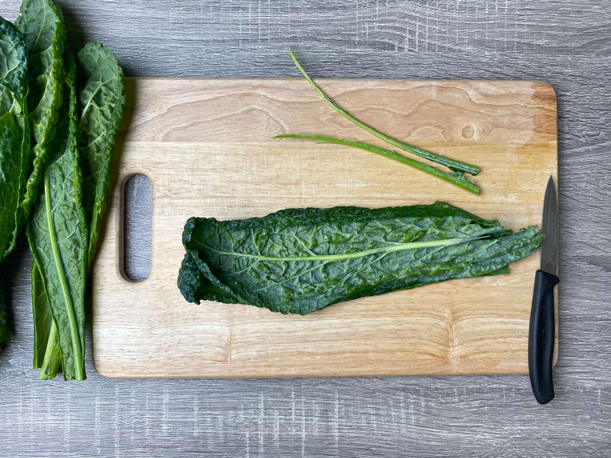 removing stems from lacinato kale on a wooden cutting board