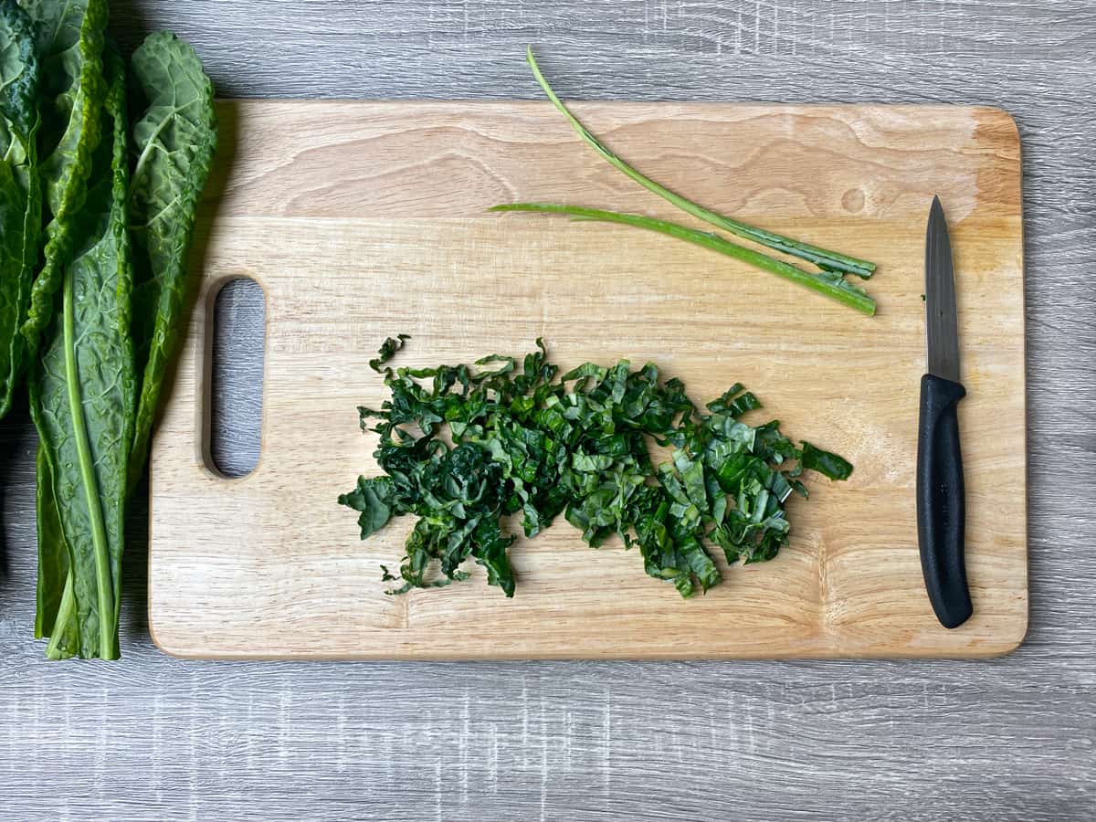 kale leaf sliced into ribbons on a wooden cutting board