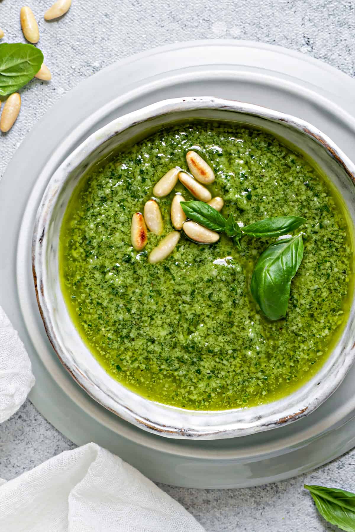 overhead shot of basil pesto in a white bowl on a white table