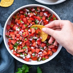 white bowl of pico de gallo salsa on a table with a bowl of tortilla chips