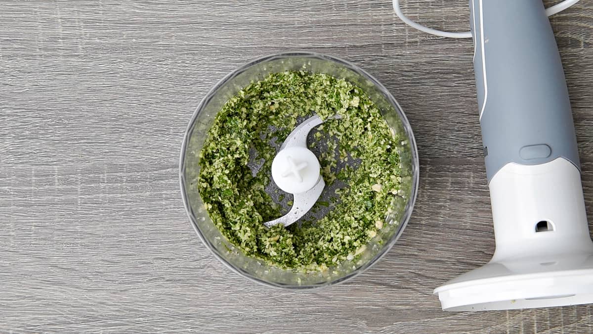 pine nuts and basil in the bowl of a chopper after cut into small pieces