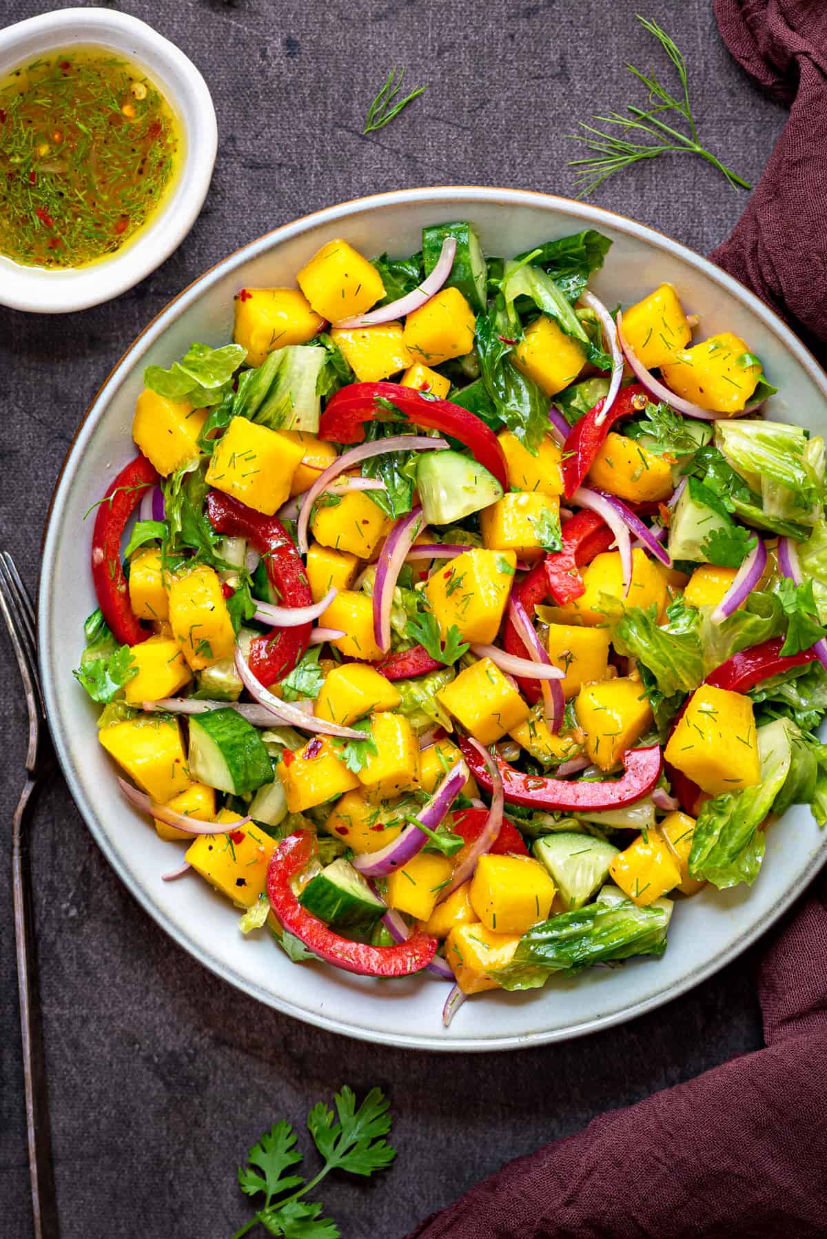 close up overhead shot of white bowl filled with fresh mango salad on a grey table