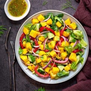 close up overhead shot of white bowl filled with fresh mango salad on a grey table