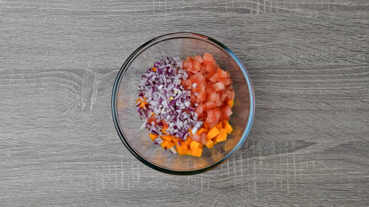 chopped tomatoes and onions added to bowl with mango