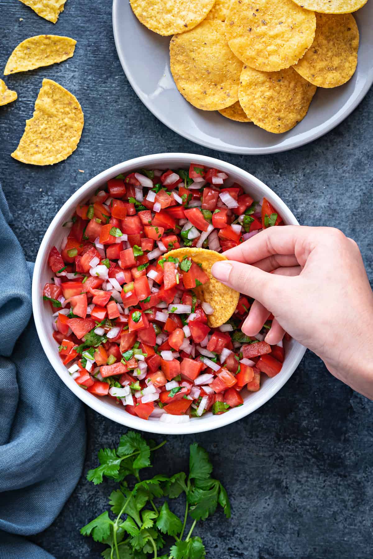 white bowl of pico de gallo salsa on a table with a bowl of tortilla chips