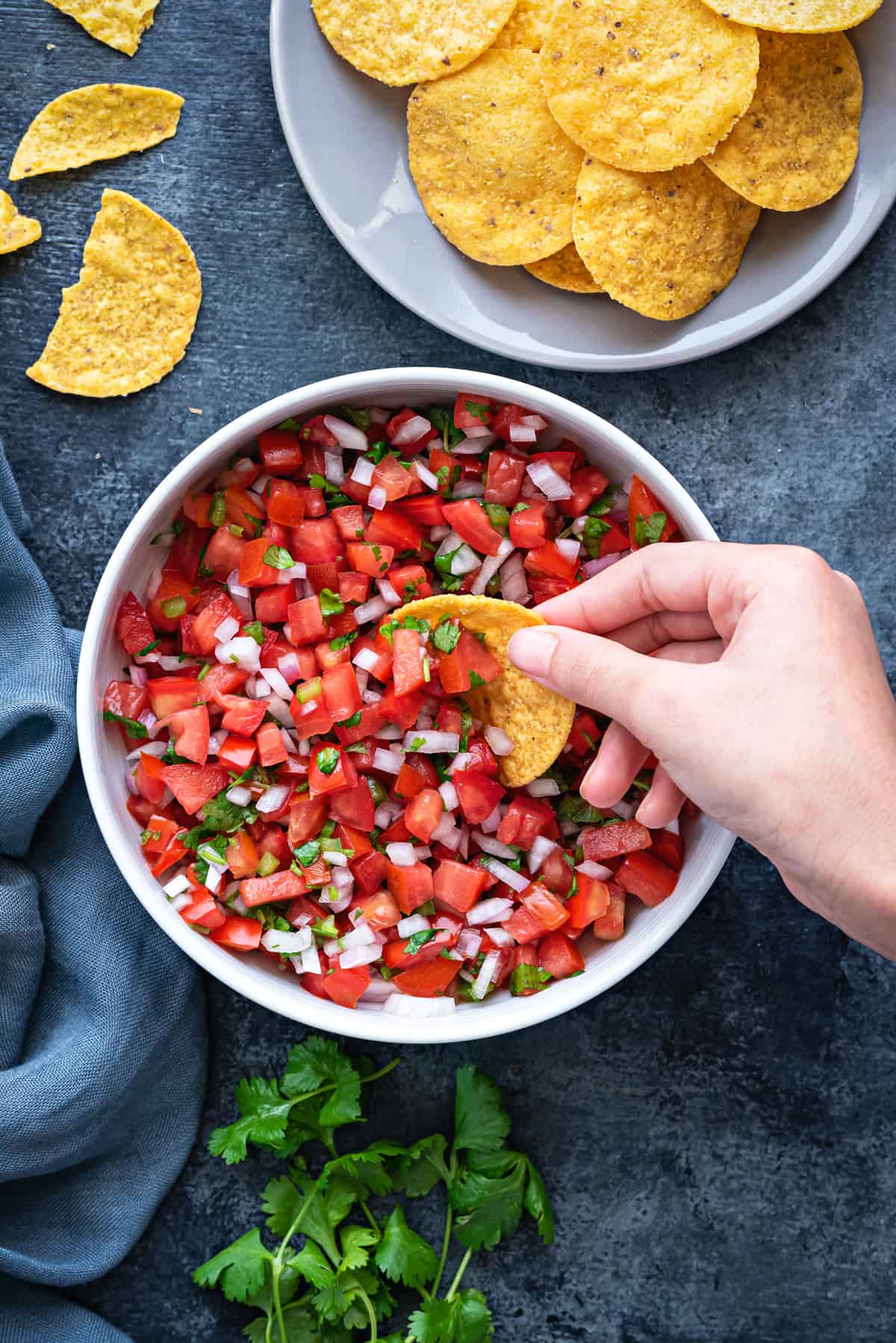 white bowl of pico de gallo salsa on a table with a bowl of tortilla chips