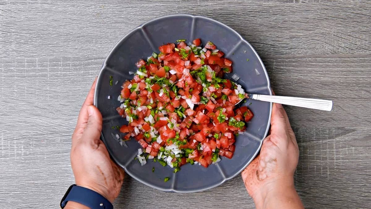 hands holding bowl of salsa after mixing