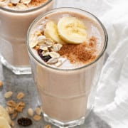 healthy muesli banana breakfast smoothies topped with sliced banana, muesli and dusted with cinnamon