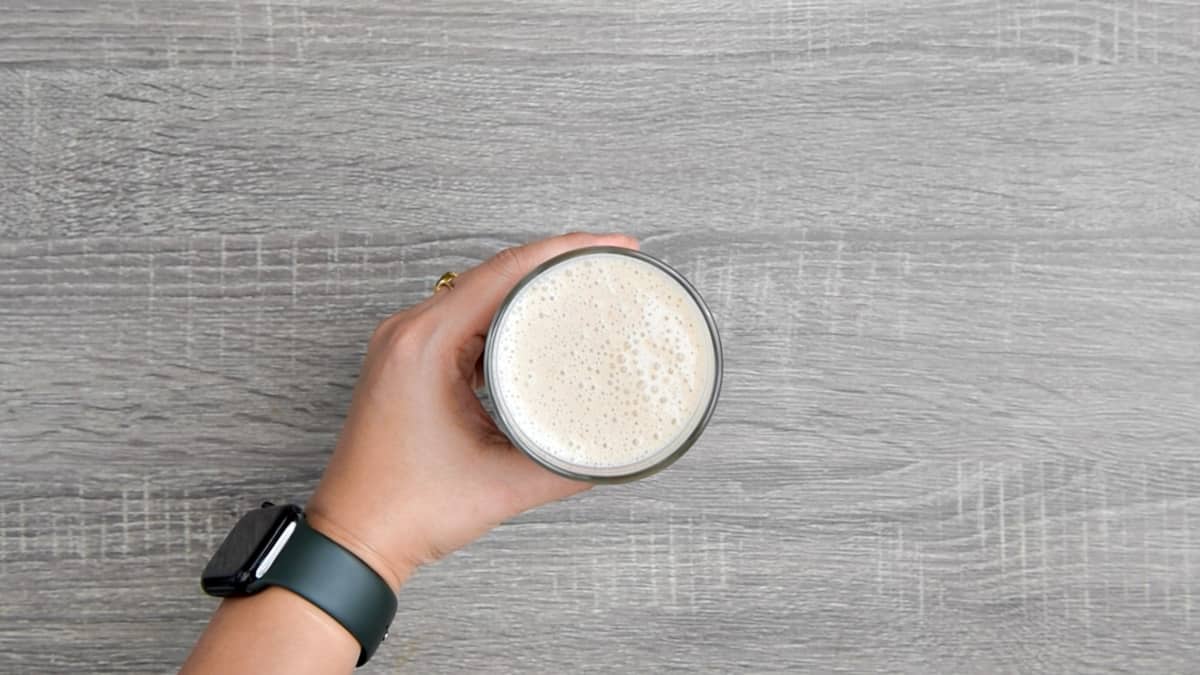 hand holding glass of banana breakfast smoothie