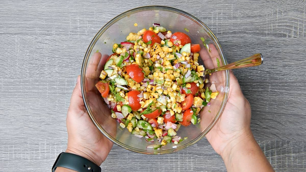 hands holding mixing bowl after tossing summer corn salad together