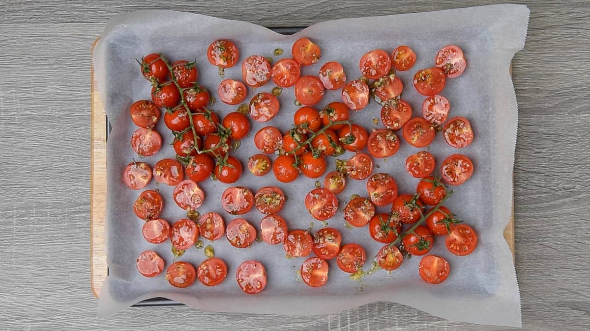 cherry tomatoes on a parchment lined baking sheet and drizzled with oil mixture