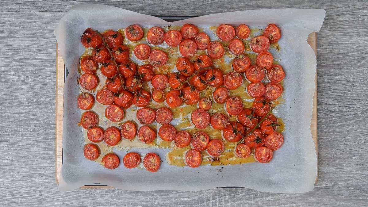 blistered cherry tomatoes on a parchment lined sheet pan after roasting