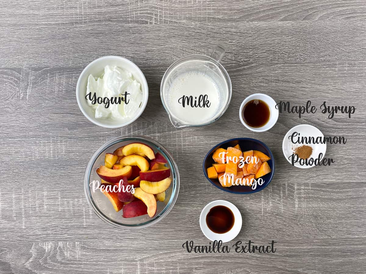 ingredients for mango peach smoothie measured out into bowls and laid on a table