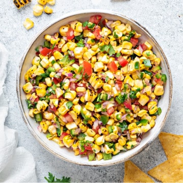 overhead shot of a white earthenware serving bowl filled with roasted corn salsa