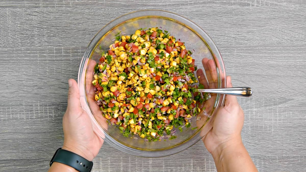 hands holding mixing bowl after tossing corn salsa together