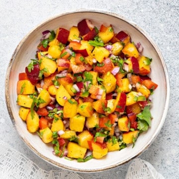 white earthenware serving bowl with peach salsa on a grey table