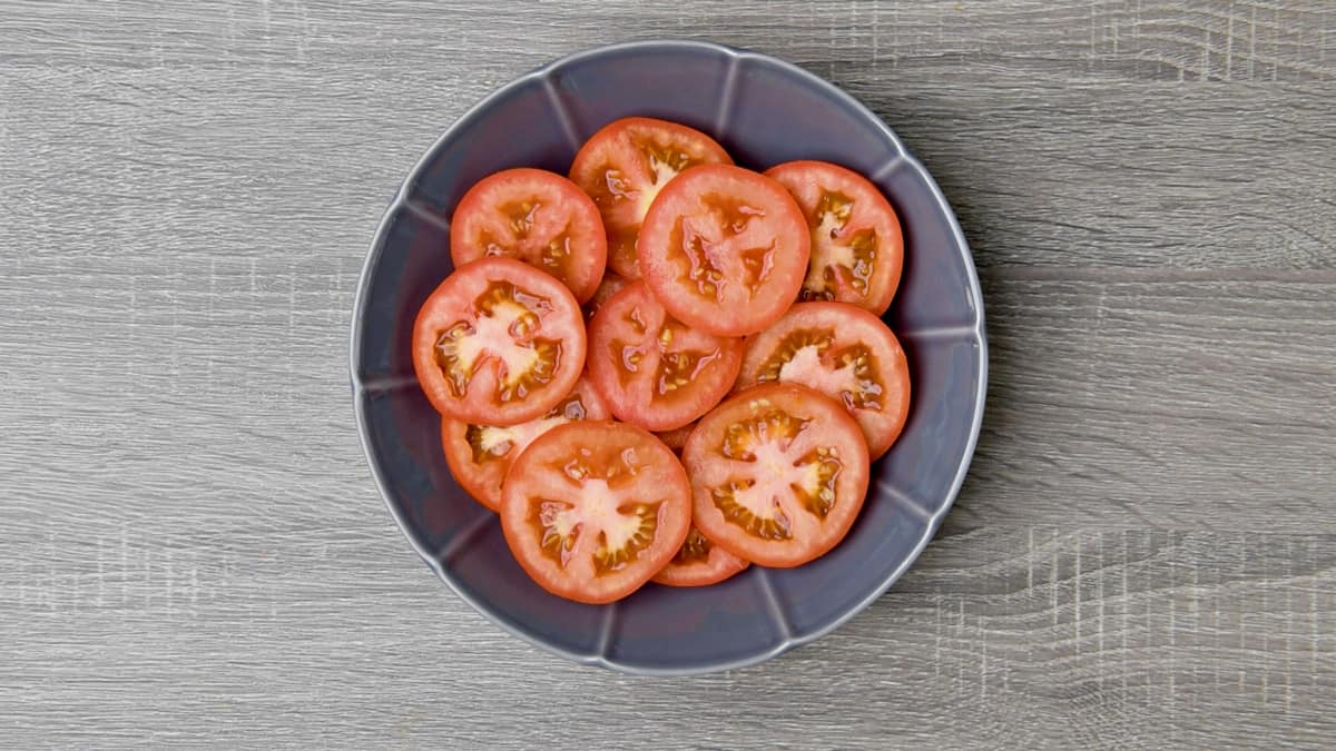 sliced beefsteak tomatoes arranged in grey shallow dish