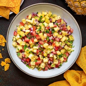overhead shot of glazed earthenware bowl filled with fresh pineapple salsa