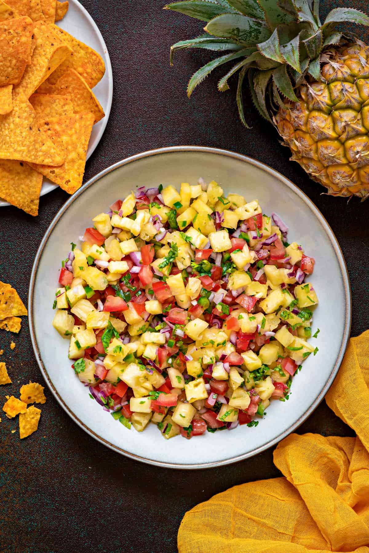 overhead shot of glazed earthenware bowl filled with fresh pineapple salsa