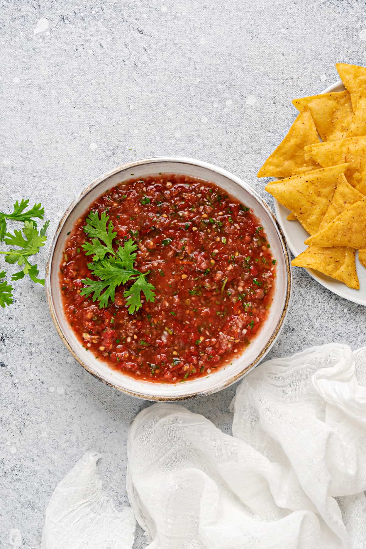 overhead shot of bowl of easy homemade salsa with a plate of tortilla chips on the side