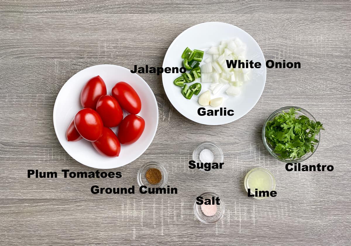 ingredients for making spicy homemade salsa recipe in bowls on a table