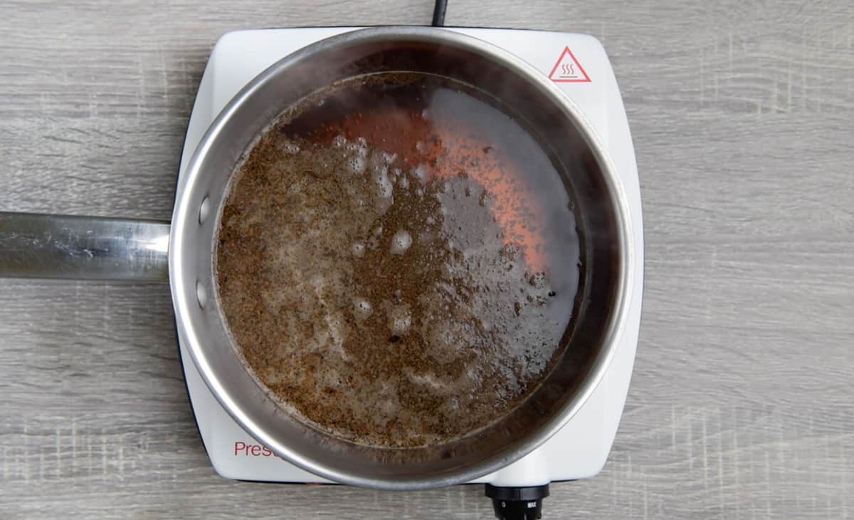 loose black leaf tea simmering in water in a medium sauce pan