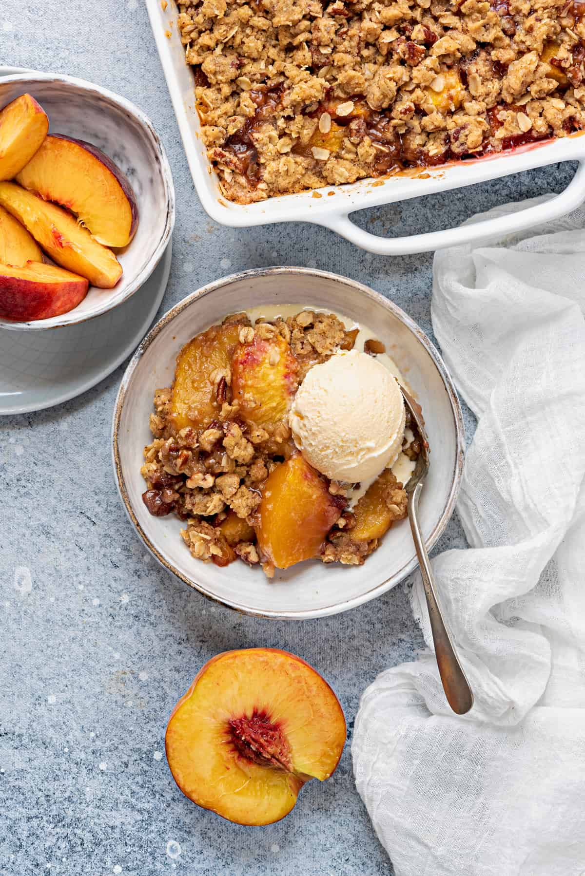 overhead shot of casserole dish, and a serving bowl of peach crisp with a scoop of ice cream