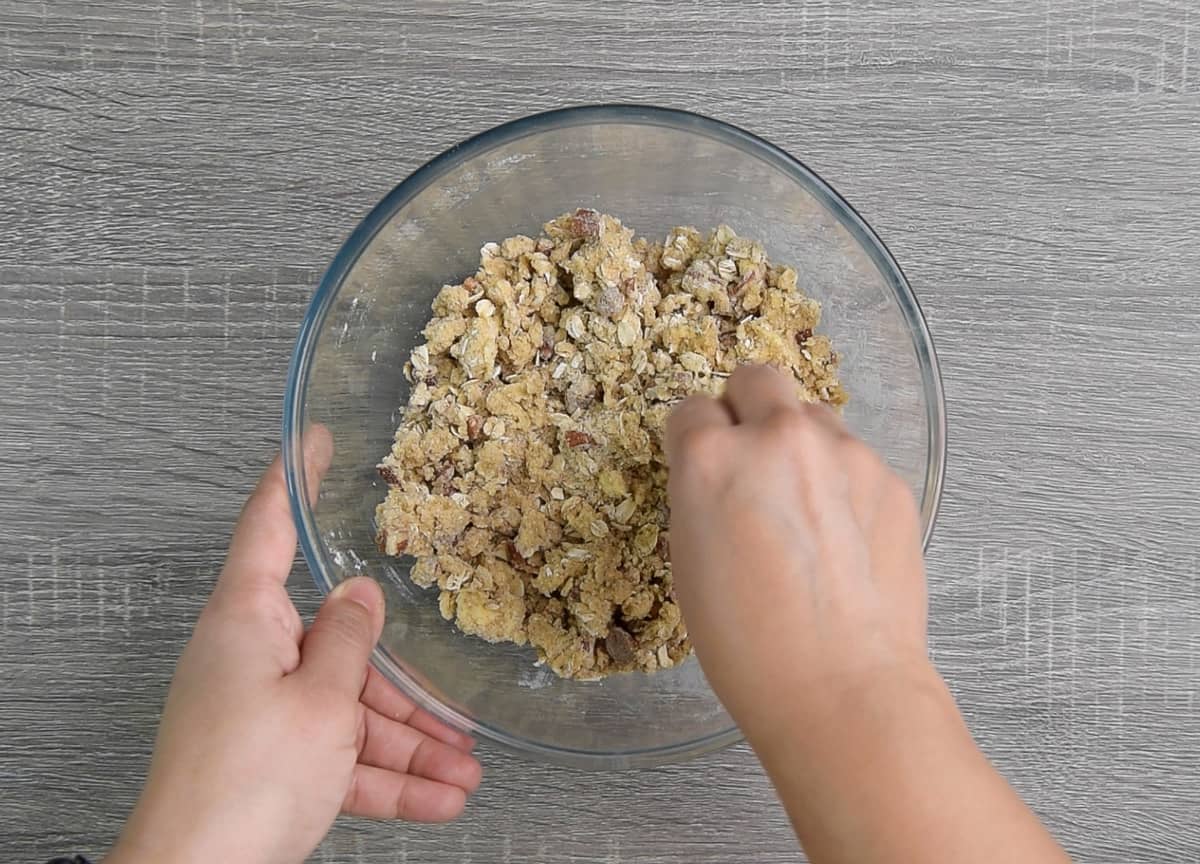 hands mixing fruit crisp topping ingredients together