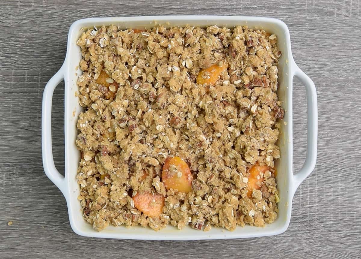 square white baking dish filled with unbaked peach crisp