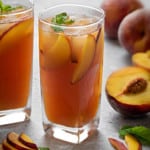 a tall glass with refreshing peach iced tea, peach slices and some fresh mint