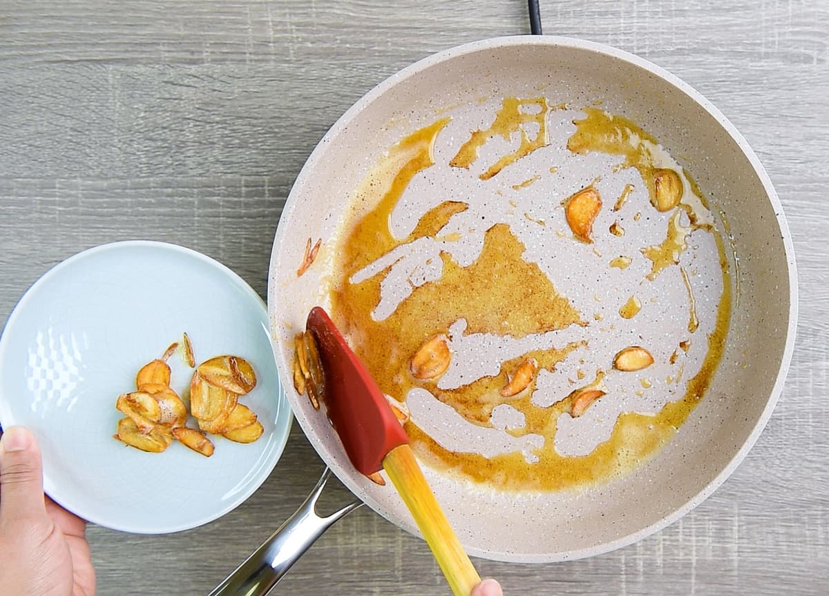 scooping out garlic chips from the browned butter to save for later