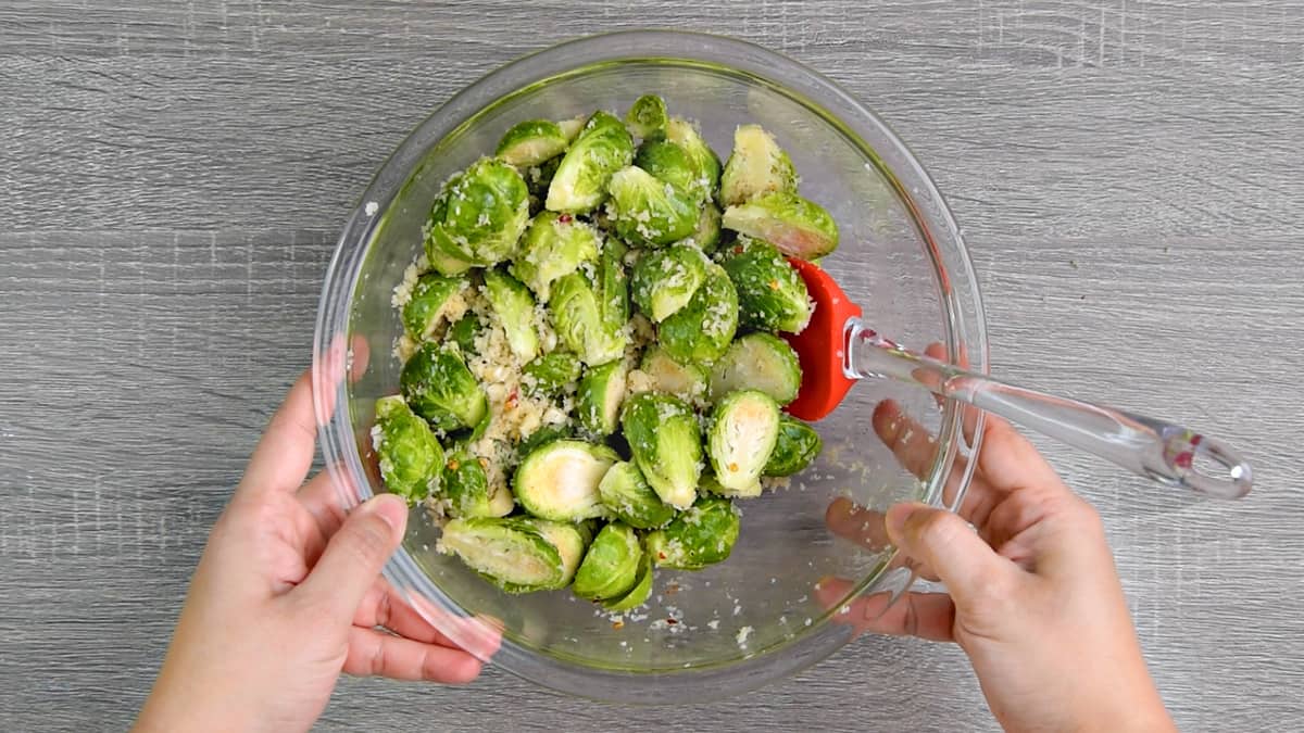 hands holding a mixing bowl after tossing brussels sprouts with oil, panko and seasonings