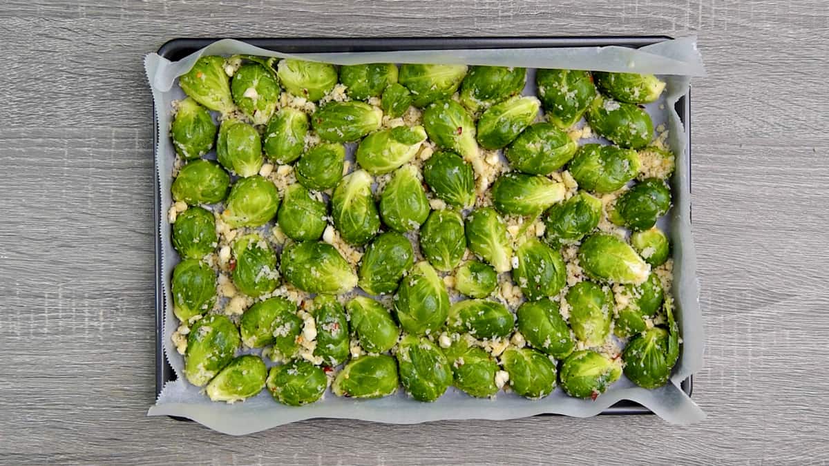 halved, tossed brussels sprouts arranged on a parchment lined sheet pan with cut sides facing down