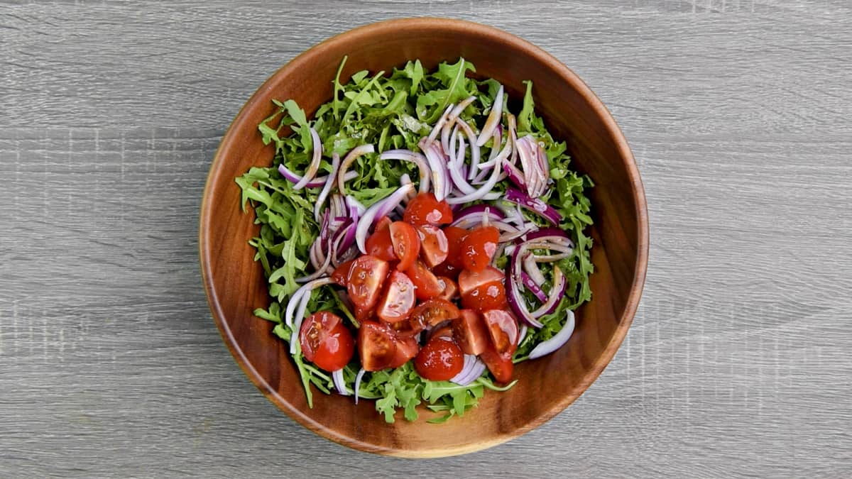 arugula, onions, tomatoes in wooden bowl for salad