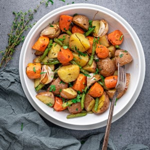one plate of roasted carrots and potatoes with fresh herbs and a fork