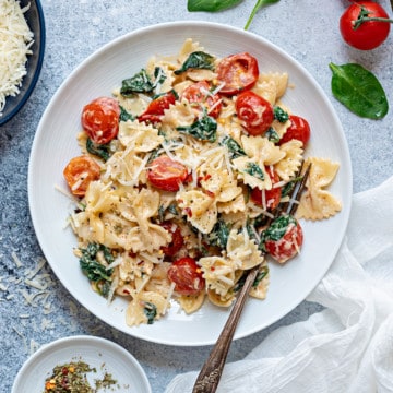 one white plate filled with spinach with tomatoes and pasta