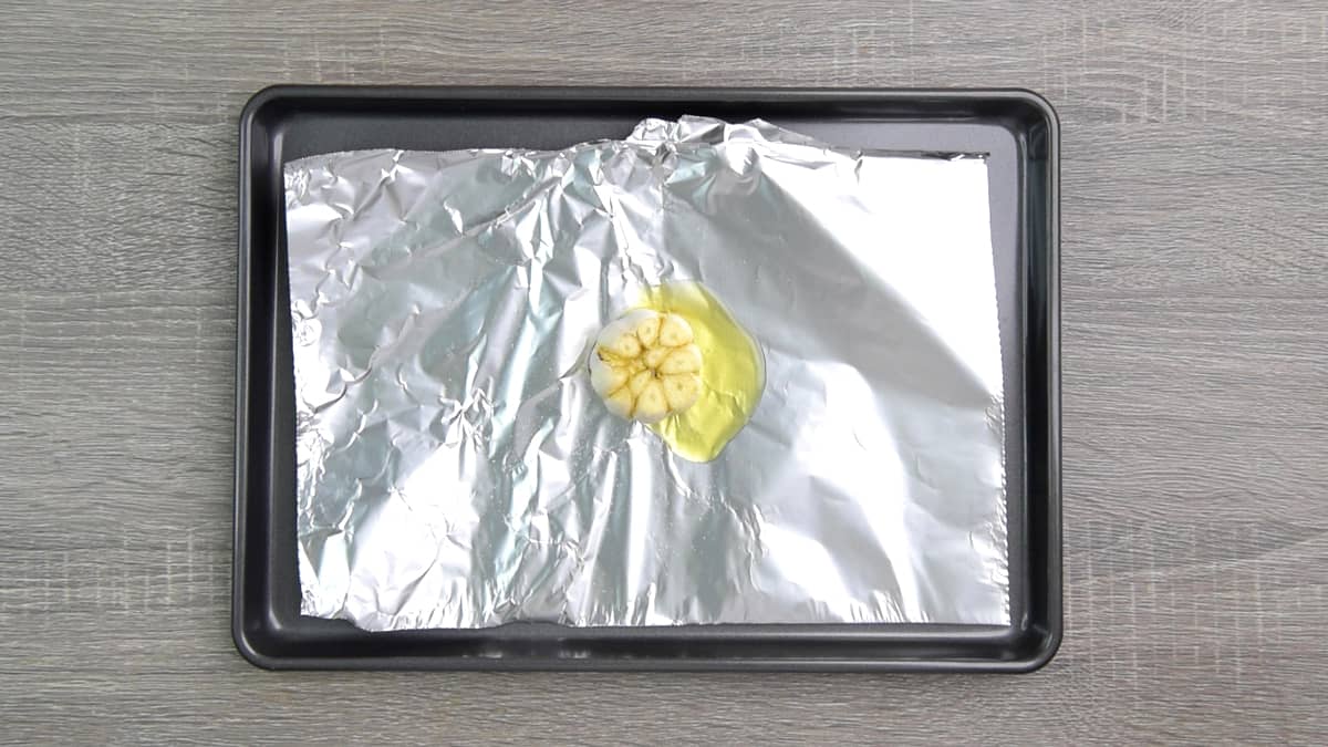 head of garlic with olive oil on aluminum foil 