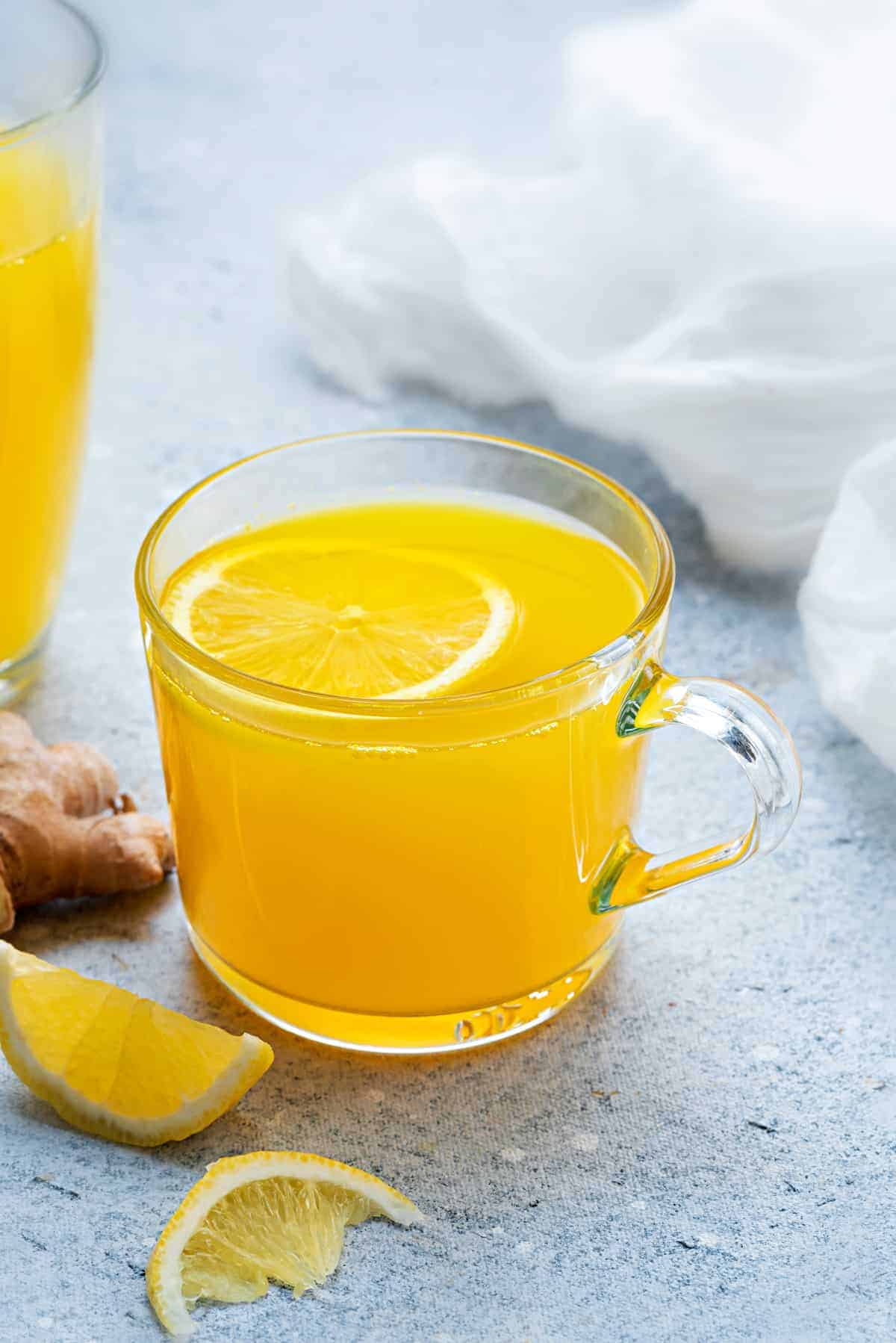 Ginger turmeric tea in two glass mugs with lemon slice.
