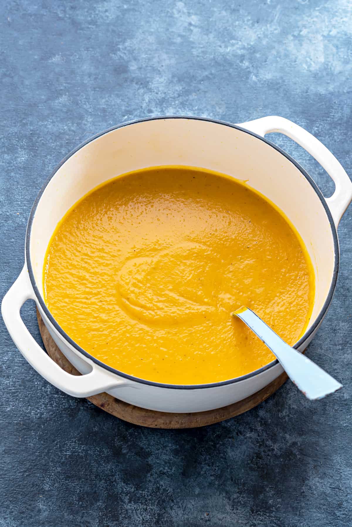 Easy Butternut Squash Soup one white pot filled with creamy butternut squash soup with spoon