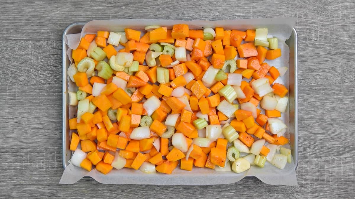freshly chopped squash, celery, and onions on baking sheet pan