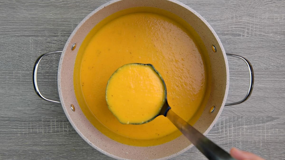 one pot of butternut squash soup with a ladle 