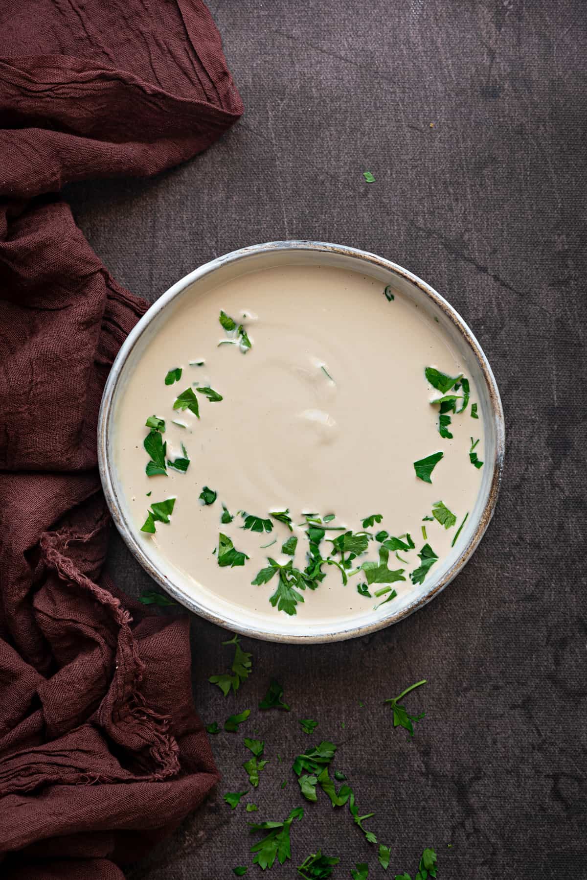 one white bowl with tahini sauce with parsley 
